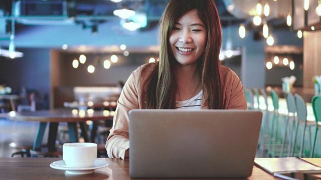 4k视频场景的亚洲女商人工作与笔记本电脑和喝咖啡在咖啡馆和共同工作空间，商业和生活方式的概念视频素材