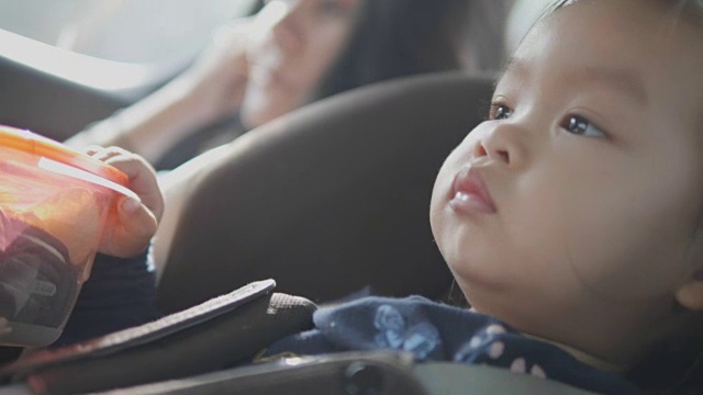 一个亚洲小女孩旅行，坐在安全的汽车上，美丽的孩子对新的地方和等待她的旅程的冒险感到惊讶和感兴趣。视频素材