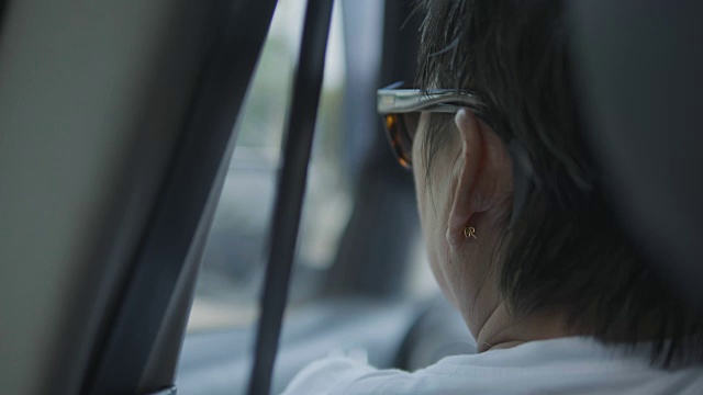 年长的亚洲女人在旅行，坐在车里等待她的旅程。视频素材