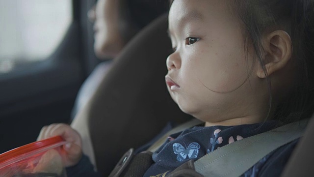 一个亚洲小女孩旅行，坐在安全的汽车上，美丽的孩子对新的地方和等待她的旅程的冒险感到惊讶和感兴趣。视频素材