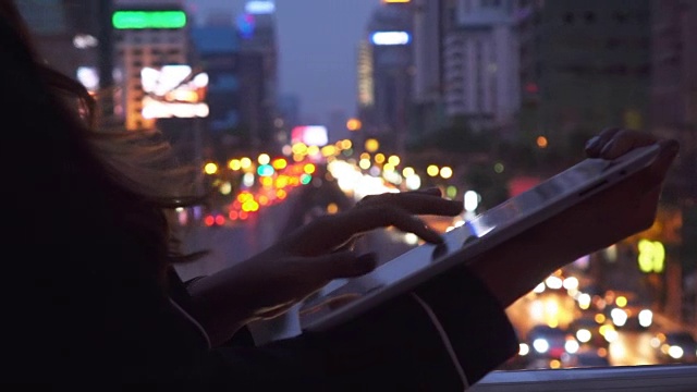 晚上在城市里使用平板电脑的女人视频素材