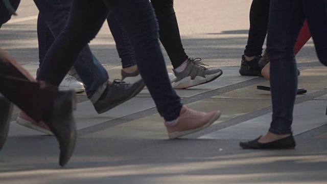 人们在城市中过人行横道。在人行横道上行走的人群的腿。慢动作视频素材