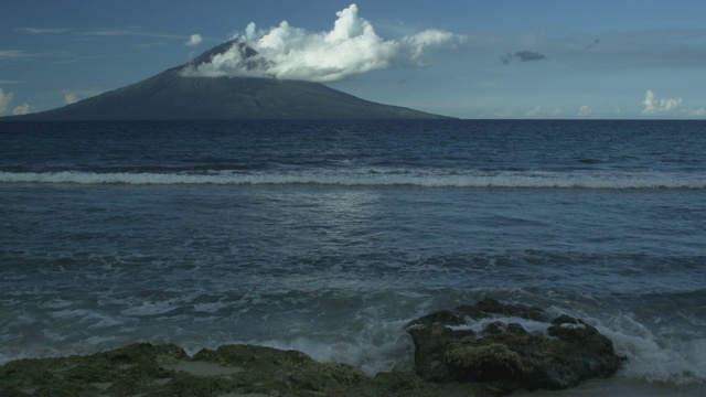 火山与云从大陆，海浪冲刷，马纳姆，巴布亚新几内亚，2009年4月视频下载