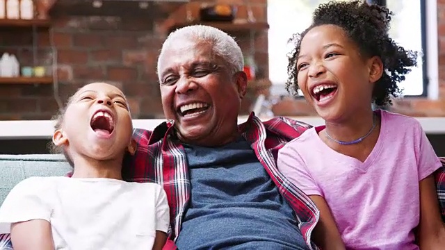 爷爷和孙女坐在沙发上大笑的肖像视频素材