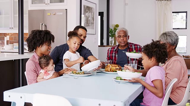 多代同堂的家庭围坐在家里享受美食-慢镜头拍摄视频素材