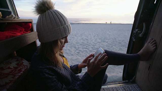 一名年轻女子戴着无檐帽，在露营车里放松视频素材