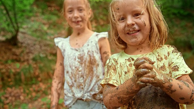 小女孩笑着和她的朋友们在森林小溪里玩，而她全身都是泥视频下载