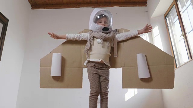卧室里的女孩打扮成飞行员或飞行员，假装驾驶着一架纸飞机，并想象自己在天空中自由飞翔。视频素材