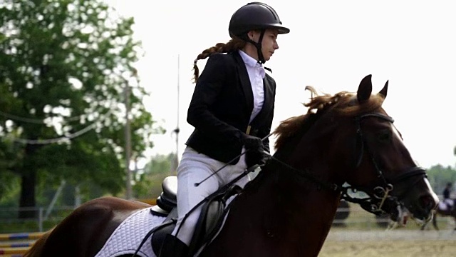 慢镜头:一个年轻的女骑师在马上表演马术比赛。夏天的一天。视频下载
