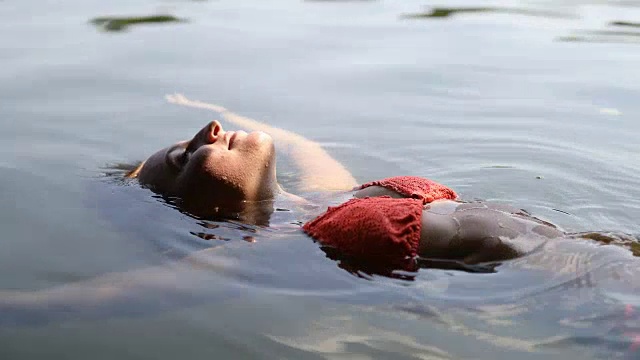 放松的年轻女子在比基尼漂浮在湖上视频下载