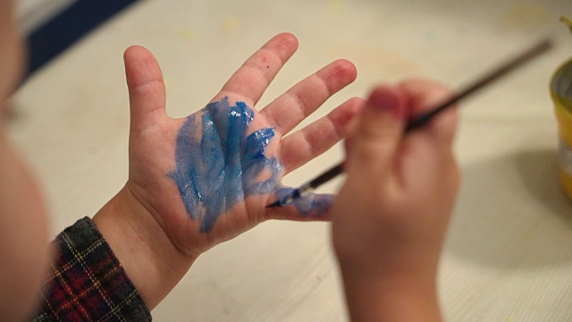 有趣的孩子用颜料画他的手。视频素材