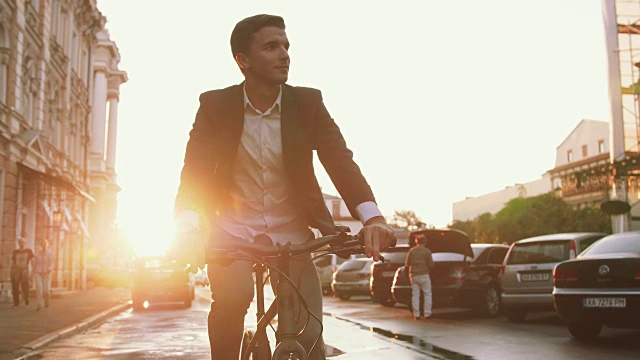 日出时，英俊的年轻人骑着自行车在市中心的街道上行驶，慢镜头视频素材