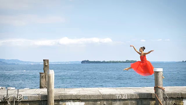 一个美丽的轻芭蕾舞女演员的肖像，在一个茂盛的红色连衣裙，而她正在跳舞。视频素材