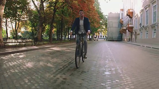 日出时，帅气的年轻人在市中心公园的街道上骑着自行车，慢镜头，跟踪镜头，万向节视频素材