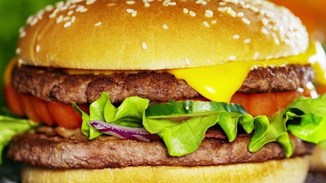 汉堡加洋葱、西红柿、帕尔马干酪沙拉和调味汁的汉堡，可以搭配或不搭配薯条。汉堡包是一种典型的美国食品，一种快餐食品。视频素材
