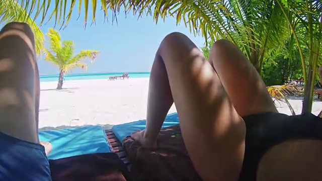 一对夫妇在马尔代夫田园诗般的热带海滩上的棕榈树下放松视频素材