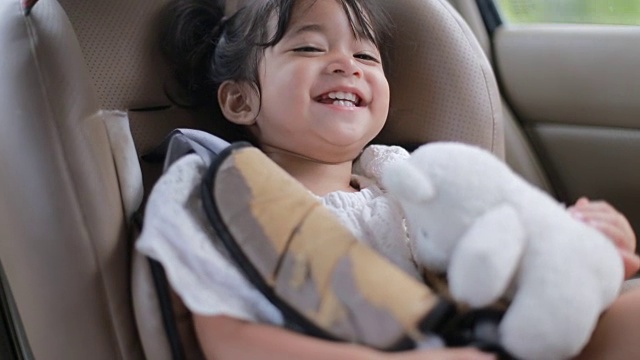 宝宝坐在安全座椅上和她的泰迪熊玩视频素材