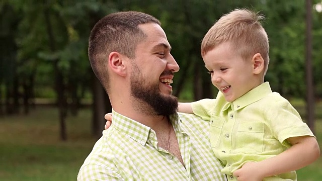 一个快乐的大胡子男人和他的儿子夏天在公园里的肖像。视频素材