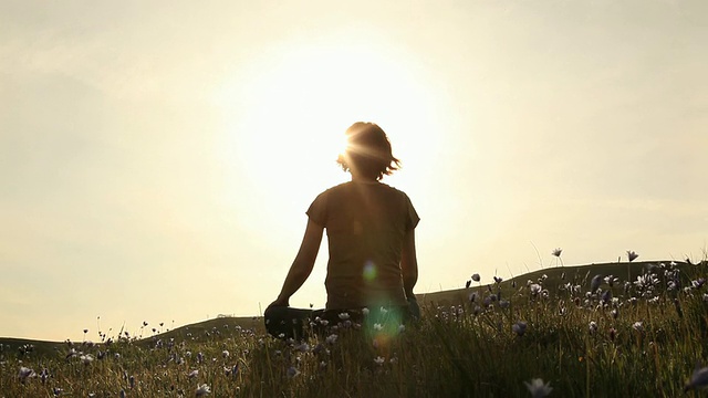 一个女人在山顶上的剪影在夕阳下沉思视频下载