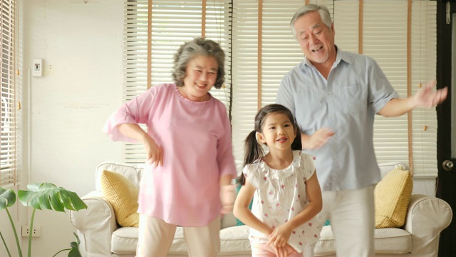 快乐的亚洲老年夫妇和他们的孙女在家里一起跳舞。高级生活方式家庭理念。视频素材