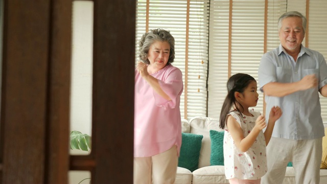快乐的亚洲老年夫妇和他们的孙女在家里一起跳舞。高级生活方式家庭理念。视频素材