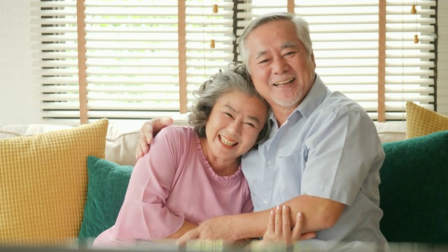 亚洲老夫妇在客厅里一起激动地看电视电影。人们以放松、养老、退休、高级生活方式为家庭观念。视频素材