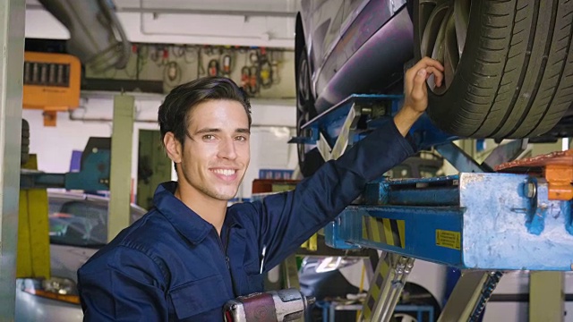 在一个车间里，一个机修工检查完机器后，竖起大拇指，微笑着说机器修好了，因为汽车修好了。视频素材