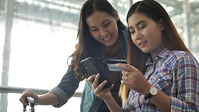 两个年轻快乐的女孩在智能手机上购物视频下载