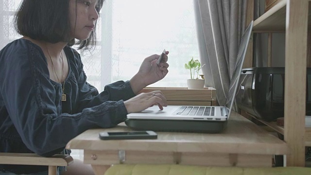 有信用卡和笔记本电脑的年轻女子在房间里在线支付账单。视频素材