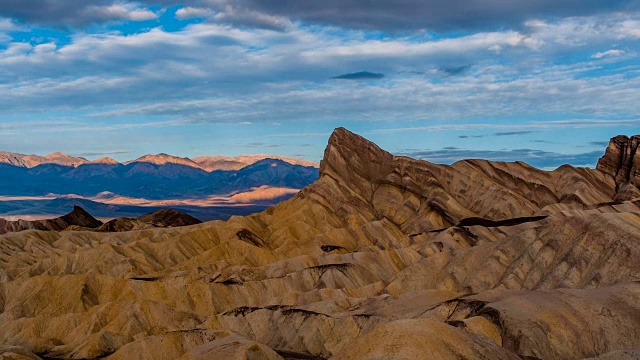在扎布里斯基点的日出-曼利灯塔和周围的岩层的日出视图的延时视频，作为春天早晨的云彩经过。扎布里斯基角，死亡谷国家公园，加州，美国。视频下载