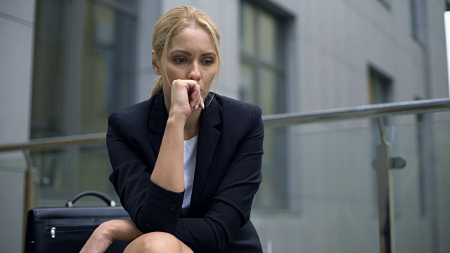 焦虑的女人坐在长椅上，担心被解雇，沮丧视频素材