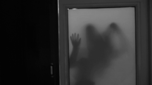 哑光玻璃窗后面幽灵女人的阴森剪影视频素材