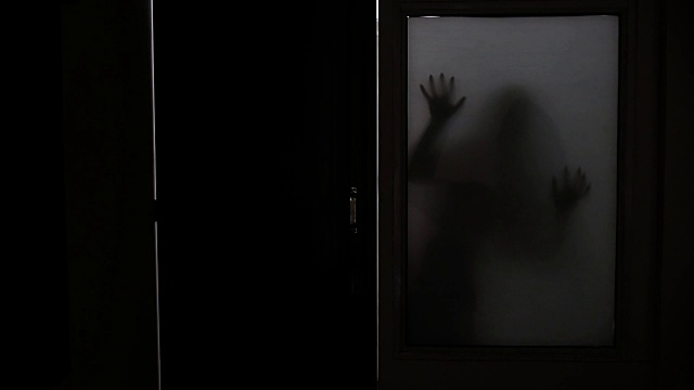 哑光玻璃窗后面幽灵女人的阴森剪影视频素材