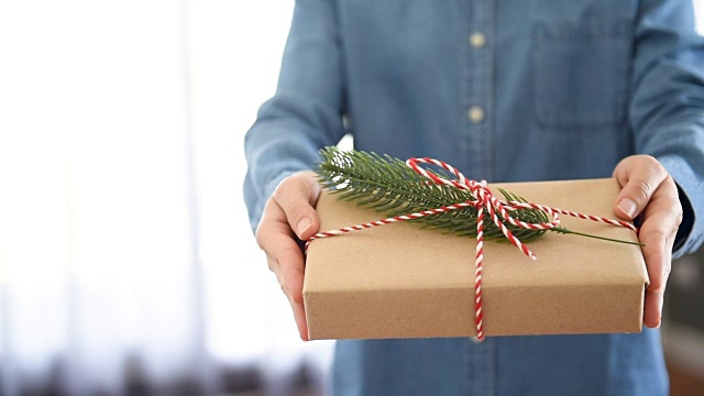 女人手捧牛皮纸礼品盒，作为圣诞和新年假期的礼物。视频素材