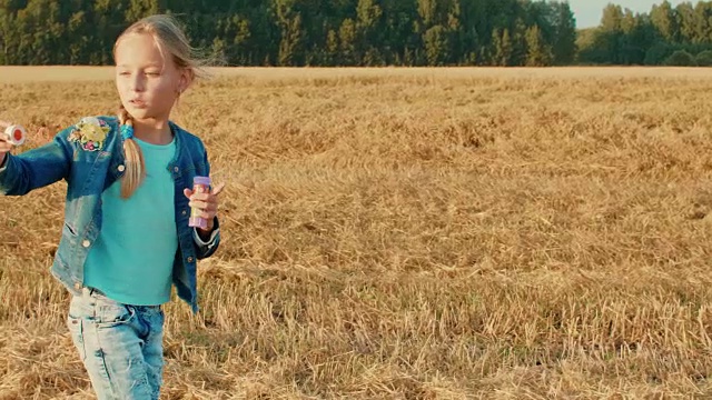 美丽的年轻女孩吹肥皂泡在旋转的秋天的田野视频素材