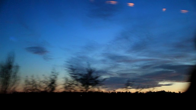 日落时路过的风景乘客POV，梦幻的风景。道路上树木和电线的剪影视频素材