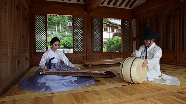 在韩国风格的房子里演奏伽倻琴(有12根弦的韩国古筝)的音乐家和打鼓的鼓手视频素材