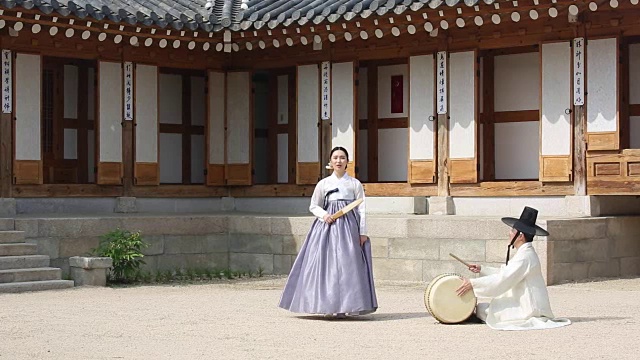 在韩国风格的房子的院子里，一个歌手和鼓手一起唱盘索里(一种由歌手和鼓手表演的韩国音乐叙事体裁)视频素材