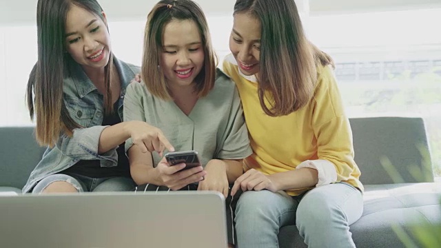 迷人的年轻亚洲女子团体看着智能手机与快乐的微笑和笑在最好的朋友概念的乐趣。视频素材