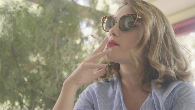 戴着太阳镜的漂亮女人抽烟视频素材