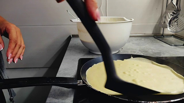 在厨房的煎锅上煎薄饼的女人视频素材