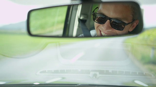 慢镜头:一名快乐的白人男子在乡间开车时唱歌。视频素材