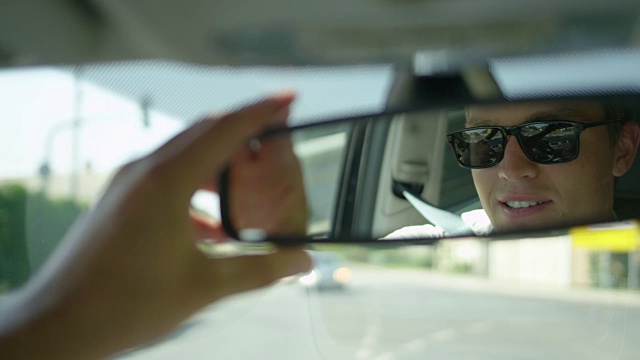 慢动作:年轻的男性司机调整后视镜看着自己。视频素材