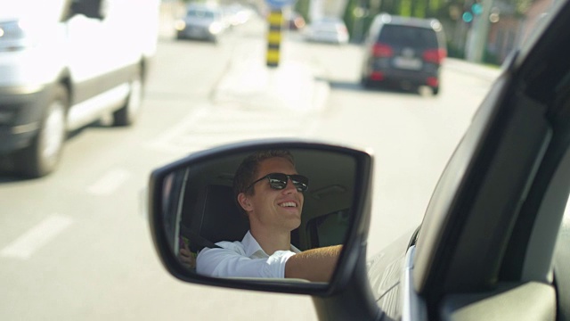 慢镜头:一个阳光明媚的日子，一个快乐的年轻白人男子开车穿过小镇。视频素材