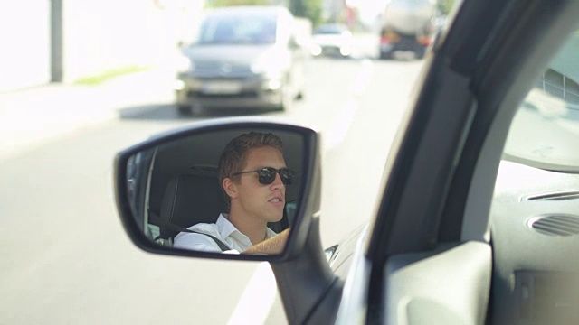 慢镜头:一名愤怒的司机从他的新车的后视镜中映出。视频素材