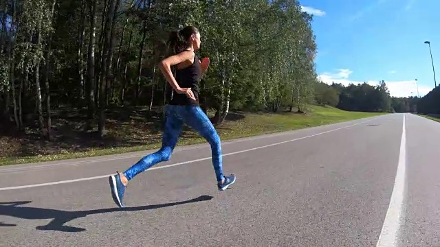 一个年轻健康的女人正在公园的小路上跑步。视频下载