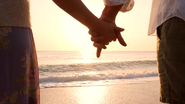 情侣们在海滩上牵着手。视频素材