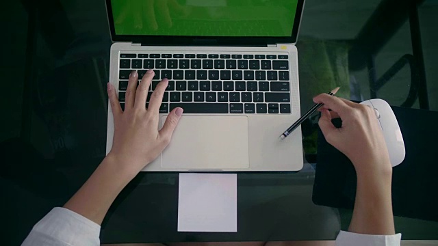 女人用绿色屏幕在笔记本电脑上打字的俯视图视频素材