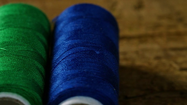 微距拍摄的彩色卷与缝纫线织物。该卷来在所有颜色和色调与缝纫针和线各种假发。视频下载