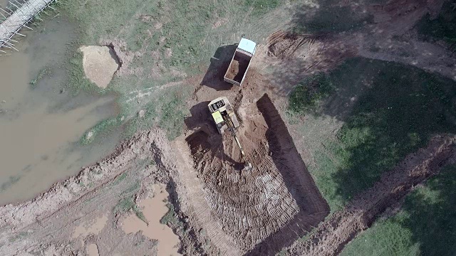 鸟瞰图:挖掘机将土装入一辆小卡车的静态视图视频素材